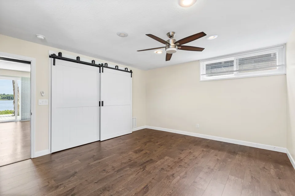 Primary bedroom with wood-look flooring and barn-style doors