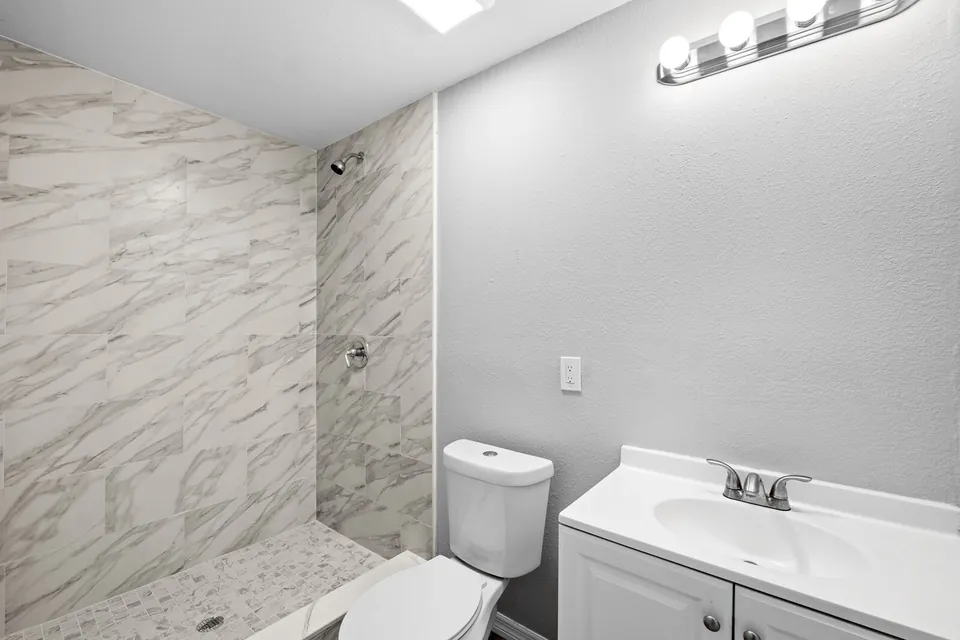 Bathroom with tiled shower and white vanity