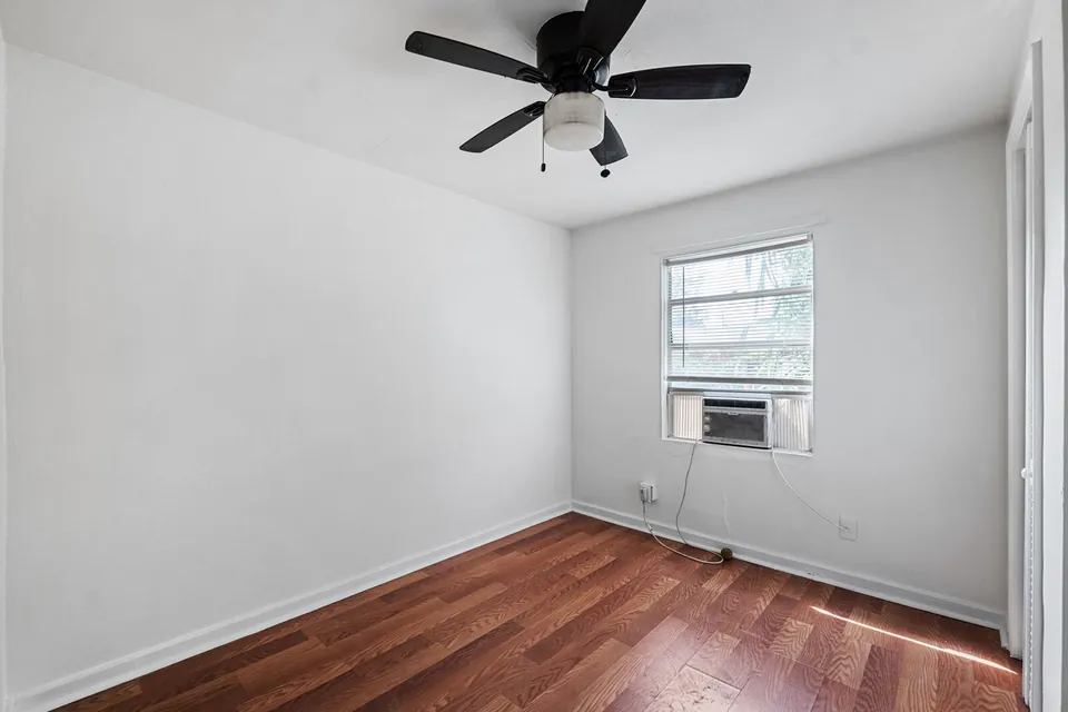 Bedroom with ceiling fan and wall air conditioner